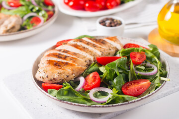 Fototapeta na wymiar Salad with grilled chicken fillet meat, fresh vegetables, spinach, ruccola, red onion and tomato. Healthy menu. Diet food. Top view. Banner 