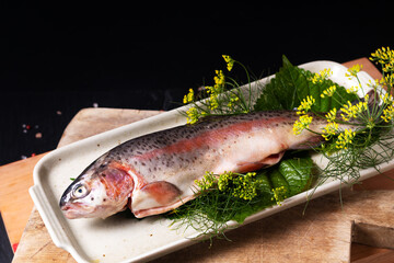 Food concept White Trout fish in in ceramic plate on wooden board on black background with copy space