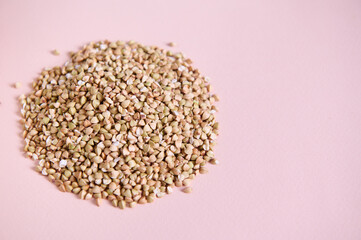 Selective focus on a heap of natural green raw not steamed buckwheat groats, grains. Ecologically...