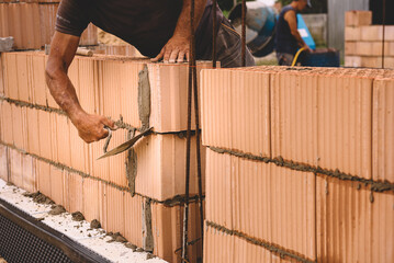 Professional construction worker laying bricks and mortar - building external house walls....