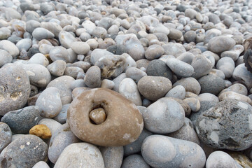 Sea pebble stones background with small stone enclosed inside a bigger on