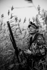 a hunter hiding in the reeds on a wild hunt, waiting for the flight of birds, the background is...