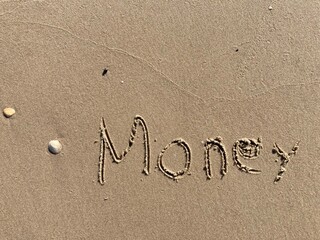 on the beach is carved with letters in the smooth sand the writing Money