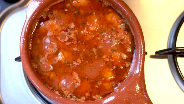 Home made gambas pil-pil or shrimps  pil-pil traditional Spanish dish. Cooked in a special clay pot. It is a very spicy dish that contains shrimps, garlic, olive oil, chilli, tomato sauce. Tilt down