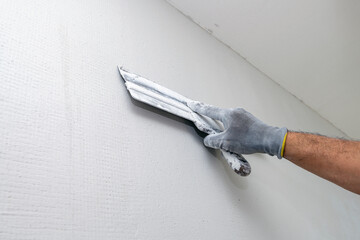 Plasterer applies plaster on the wall during repair and restoration work