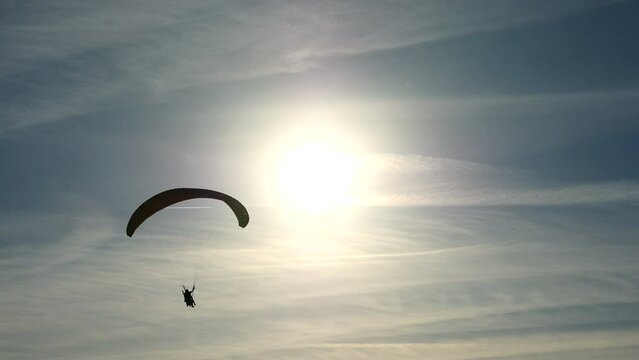 Tres personas realizando parapente en una puesta de sol.
