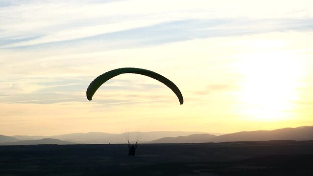 Persona realizando parapente al atardecer.