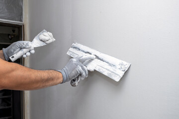 Plasterer applies plaster on the wall during repair and restoration work - obrazy, fototapety, plakaty