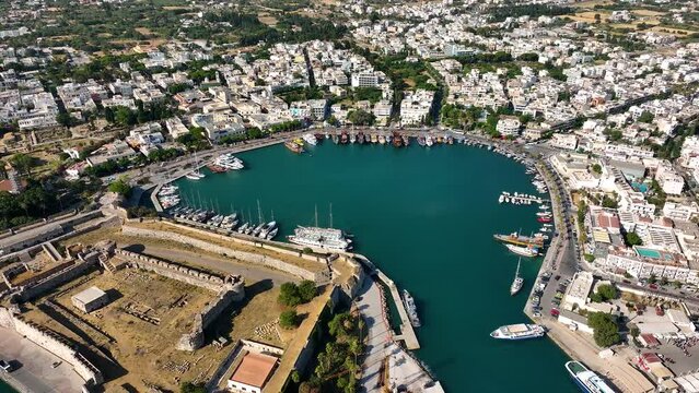 Aerial drone view of sea, harbor, boats and city architecture. Majestic view of resort town of Kos in Greece. Amazing panoramic sunrise view from 4k drone of Kos ancient castle