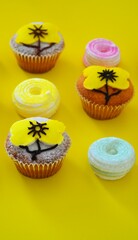Rows of muffins decorated with powdered sugar and yellow flower shaped icing on a yellow background
