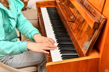 A girl on the piano learns new pieces from notes and plays at a music school.