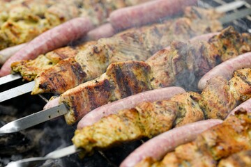 Marinated meat with grilled sausages is fried on a fire.