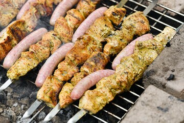 Marinated meat with grilled sausages is fried on a fire.