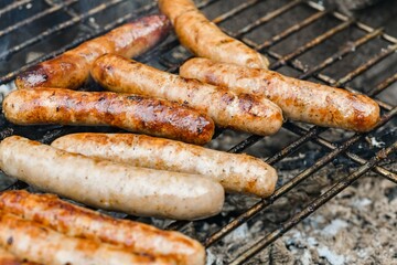 Grilled juicy sausages cooked on a campfire outdoors.