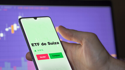Un inversor está analizando el suiza etf fondo en pantalla. Un teléfono muestra los precios del ETF SUIZA para invertir.