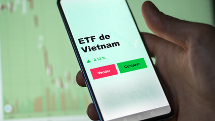 Un inversor está analizando el vietnam etf fondo en pantalla. Un teléfono muestra los precios del ETF VIETNAM para invertir.