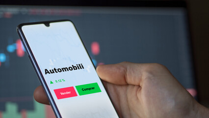 Un inversor está analizando el automobili etf fondo en pantalla. Un teléfono muestra los precios...
