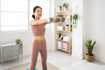 Fototapeta na wymiar Young asian woman doing exercise with dumbbells at home - Healthy lifestyle concept