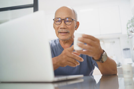 Asian Mature adult man having video call consulting with doctor on laptop from home, Telehealth or Telemedicine concept