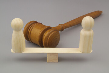 Gender equality laws concept. Male and female wooden figures on balance scales with judge gavel.