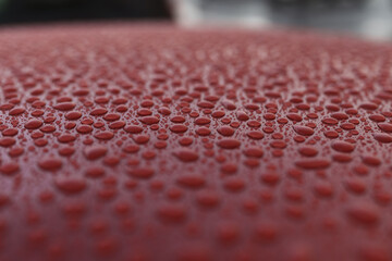 Closeup wet red car paint surface with hydrophobic ceramic coating