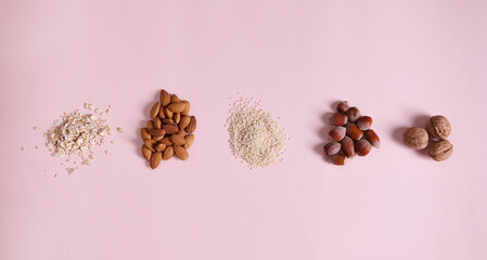 Flat lay. Stacks of organic sesame seeds, almond nuts, oat-flakes, walnut and hazelnut scattered on...