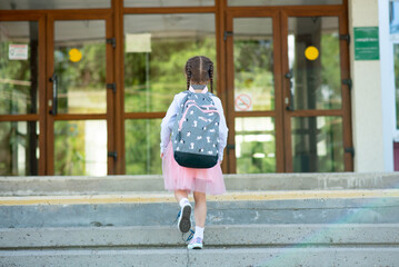 First day at school. A little school girl in first grade. Pupil of primary school. Back to school. - obrazy, fototapety, plakaty