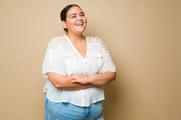 Cheerful fat latin woman smiling against a pastel yellow background - obrazy, fototapety, plakaty