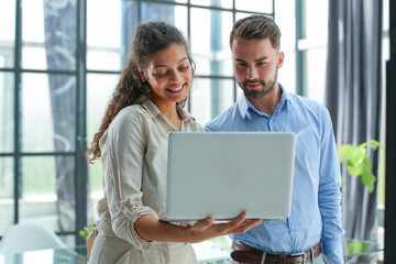 Modern business people are working using laptop and smiling while standing in the office.