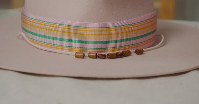 Milliner puts brown beads in row near ribbon on felt hat