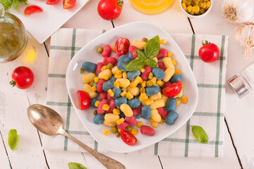 Colored gnocchi with vegetables and sweet corn.