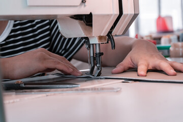 The seamstress sews at the sewing machine, threads the fabric. Women's hands