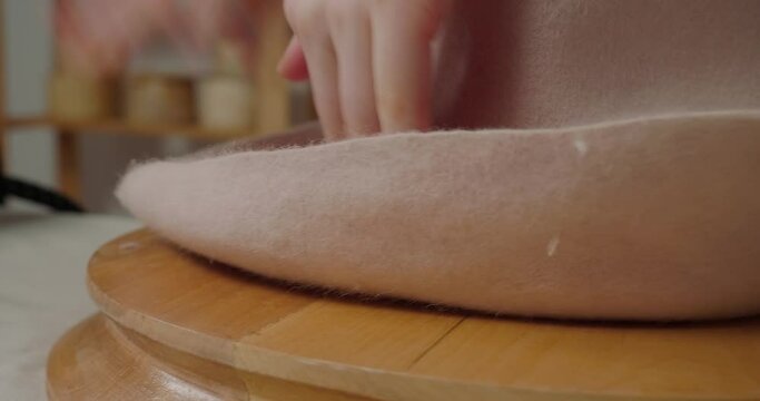 Hands of woman stretch material of felt hat to make brim