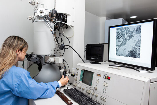 Young female scientist working at the laboratory with an electron microscope
