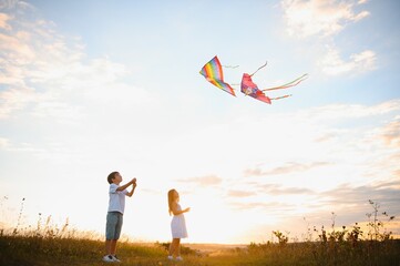 Children launch a kite in the field at sunset