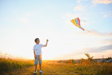 Children launch a kite in the field at sunset.