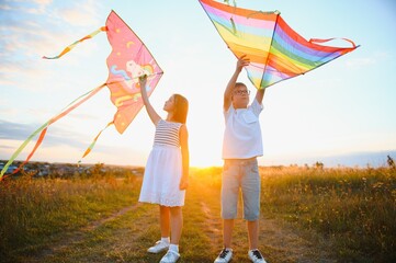 Children launch a kite in the field at sunset