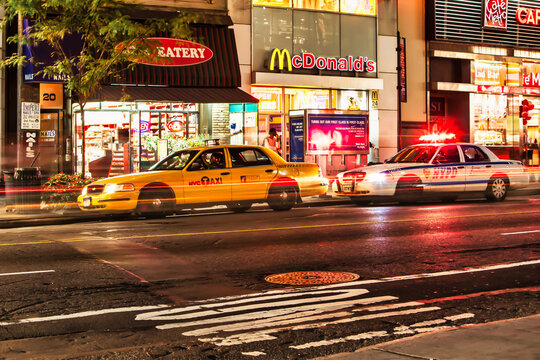 a taxi cab is stopped by a patrol car in front of Mac Donald's restaurant -New York, United States - September 22 2009
