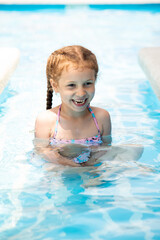 Fototapeta na wymiar A little girl in a pool of blue water. Vacation.