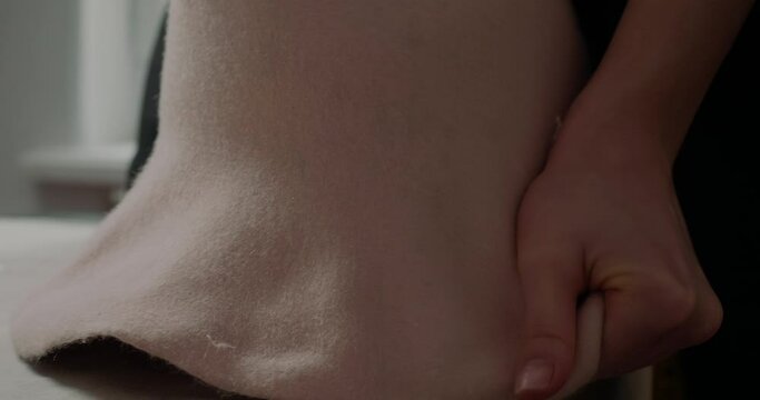 Hands of milliner pull felt hat body on mold to make shape