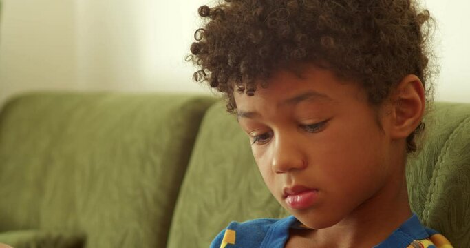 portrait of an African-American boy. A frustrated child sits at home and plays with toys experiencing bad emotions. A sensitive child.