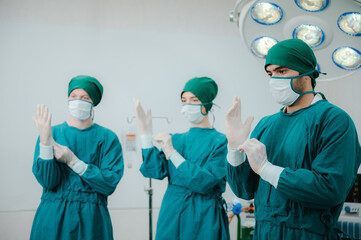 Team of male and female surgeon in srubs with surgical caps, gloves and face mask preparing for surgery in operation theatre in hospital