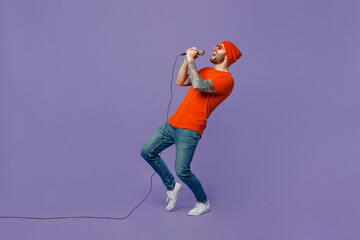 Full body side view young singer fun man 20s he wearing red hat t-shirt isolated on plain pastel...