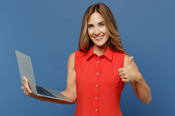 Young smiling happy freelancer IT woman 30s wear red dress hold use work on laptop pc computer show...