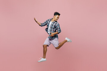 Fototapeta na wymiar Full body young smiling man of African American ethnicity wear blue shirt jump high do playing guitar gesture isolated on plain pastel light pink background studio portrait. People lifestyle concept.