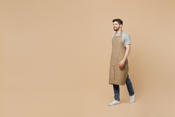 Full body side view smiling happy young man barista barman employee wear brown apron work in coffee...