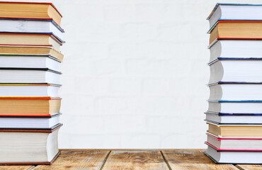 Two stacks of books on an old table against a brick wall. The space is empty in the center of the frame.