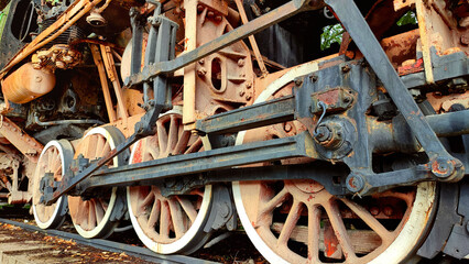 closeup rusty wheels of an old steam train - steampunk texture pattern symbol of locomotion in the industrial revolution for a background wallpaper