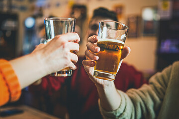 Happy friends having fun toasting beers in the pub - cheers