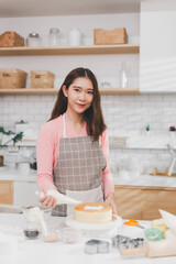 Portrait young Asian woman cooking and decoration cake with cream. Pastry chef in the kitchen decorating birthday cake. teacher instructor cake class online course, cooking and pastry skills